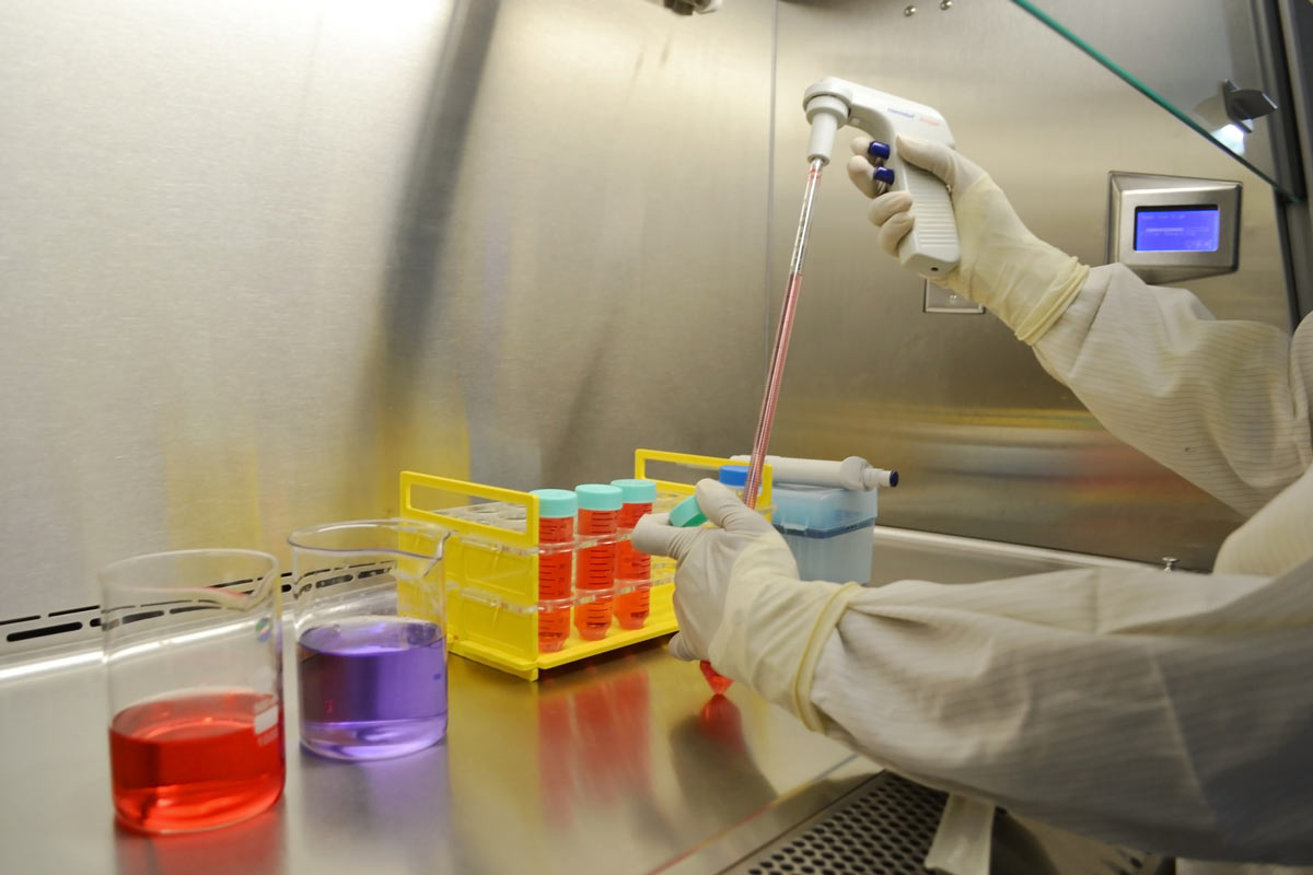 A scientist in white protective clothing and gloves conducting tests in a laboratory