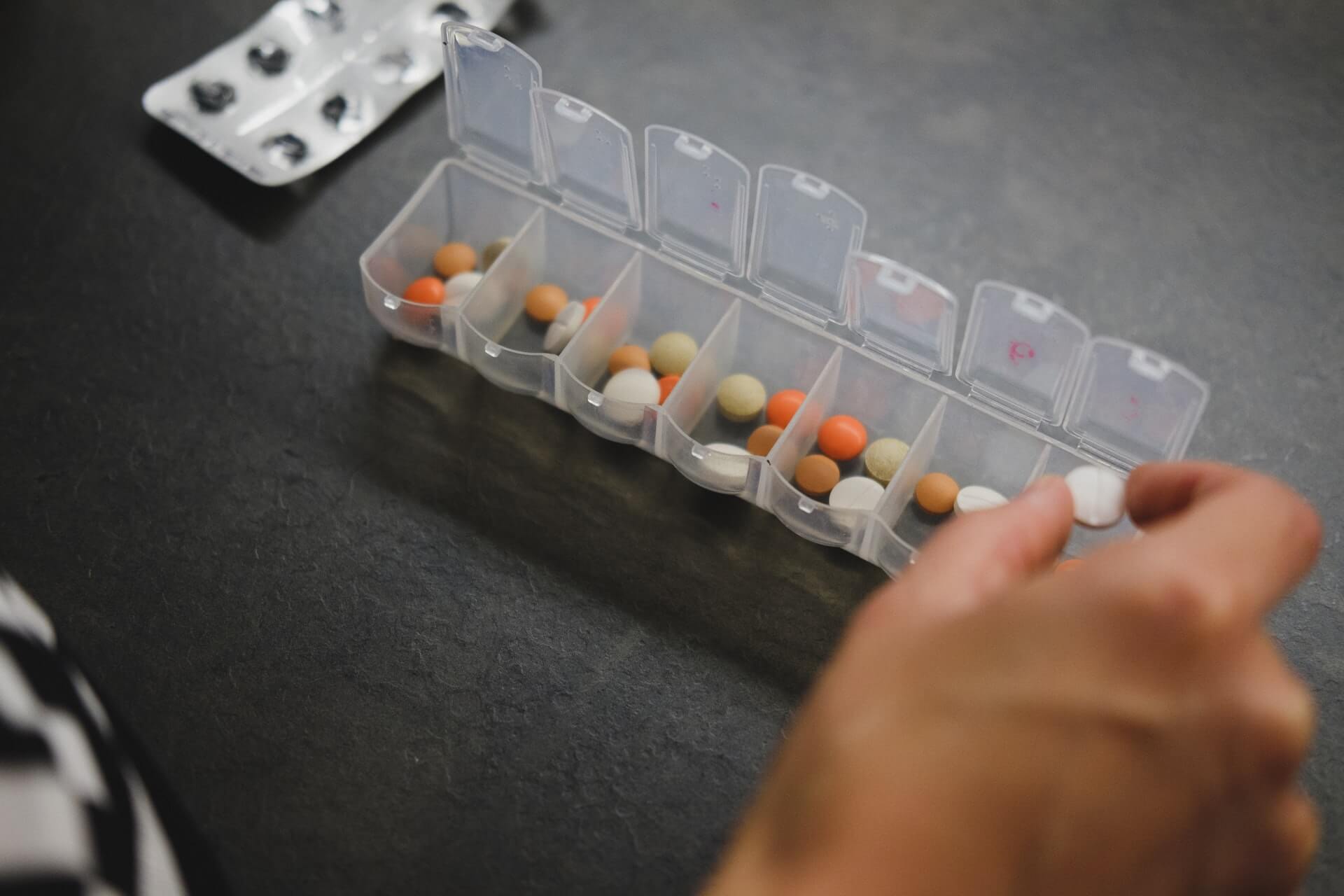 Photo of a person sorting their medications in a pill organizer