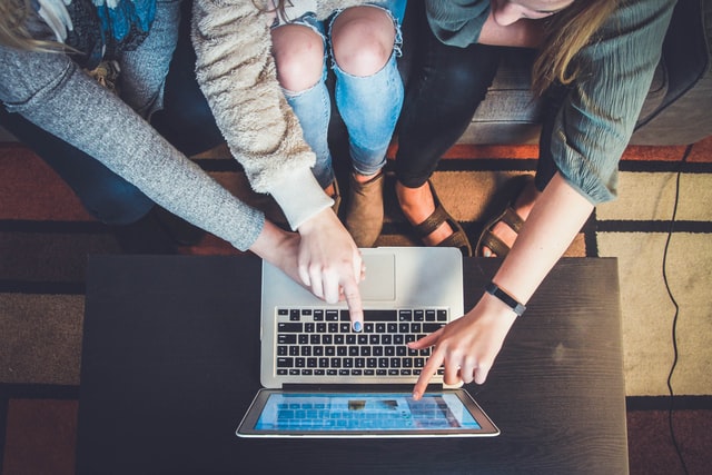 Three women pointing at a laptop screen